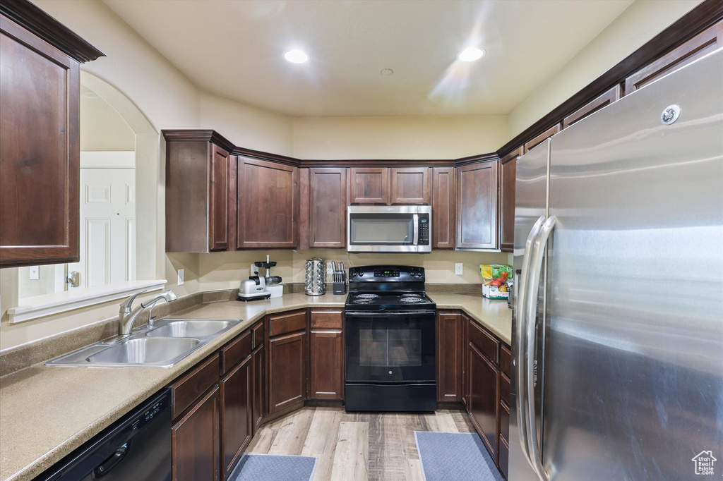Kitchen with a sink, light countertops, black appliances, recessed lighting, and light wood finished floors