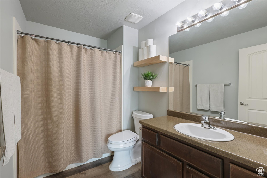 Full bathroom with wood finished floors, toilet, a textured ceiling, and vanity