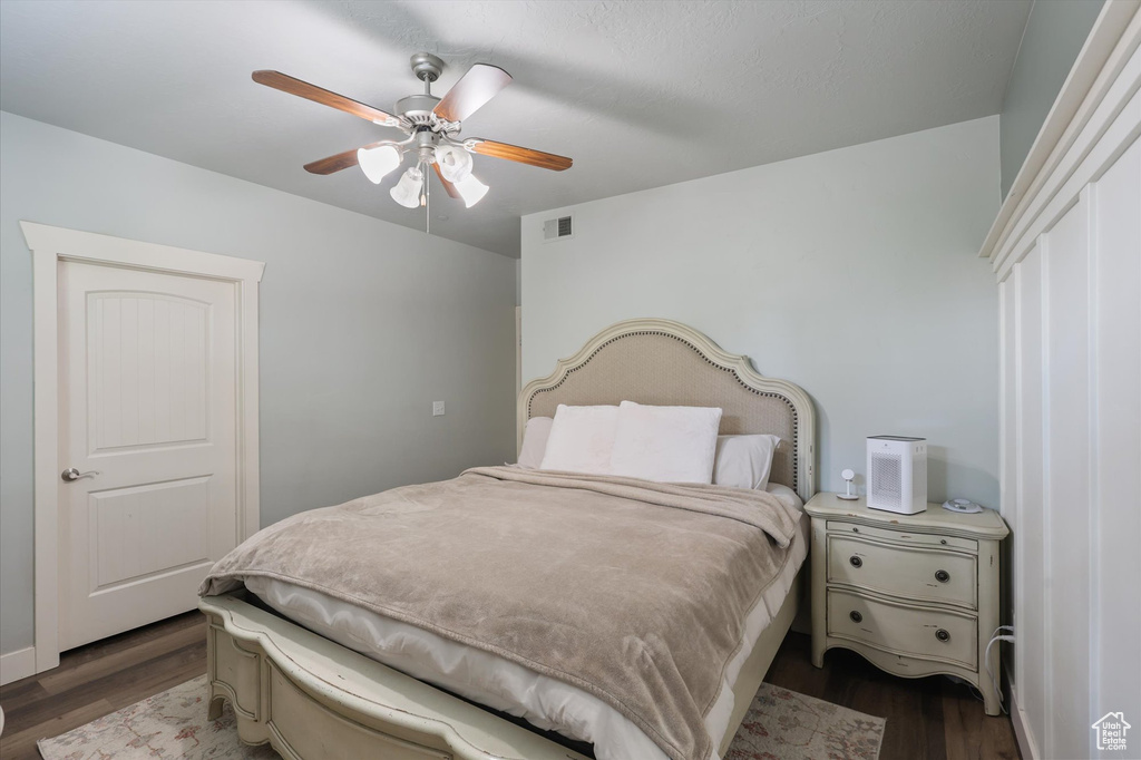 Bedroom with dark wood-type flooring, visible vents, and a ceiling fan