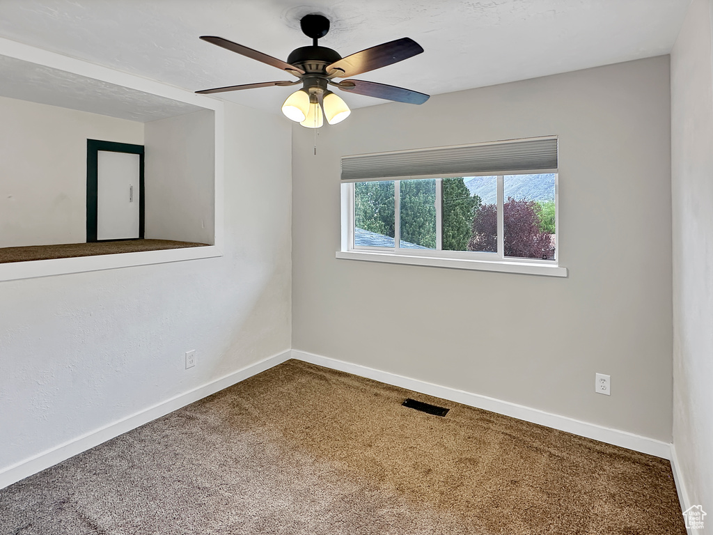 Spare room featuring baseboards, visible vents, ceiling fan, and carpet floors