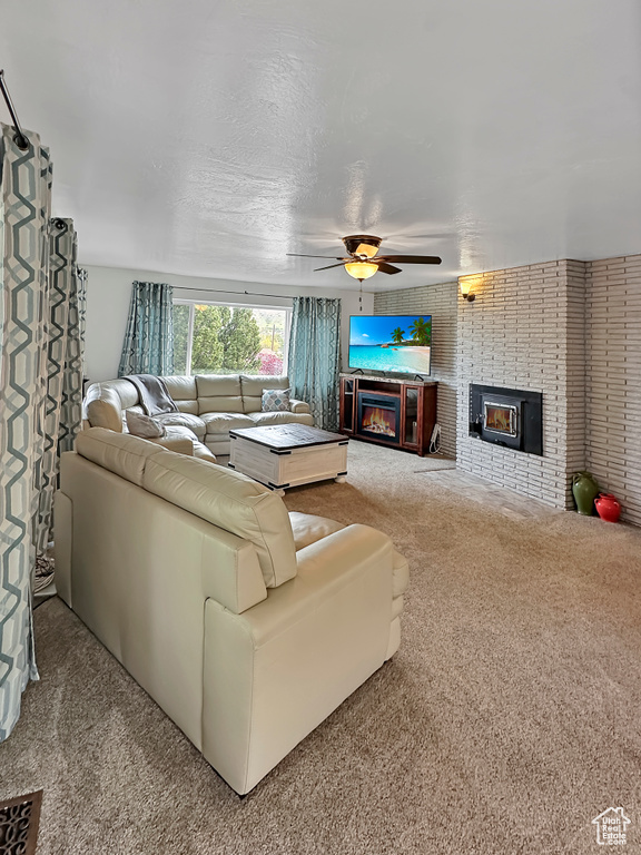Living area with a ceiling fan, carpet, and a fireplace