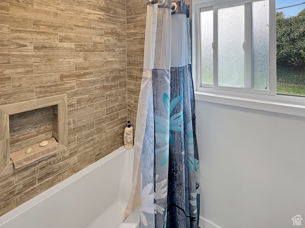 Bathroom with shower / bath combination with curtain and a wealth of natural light
