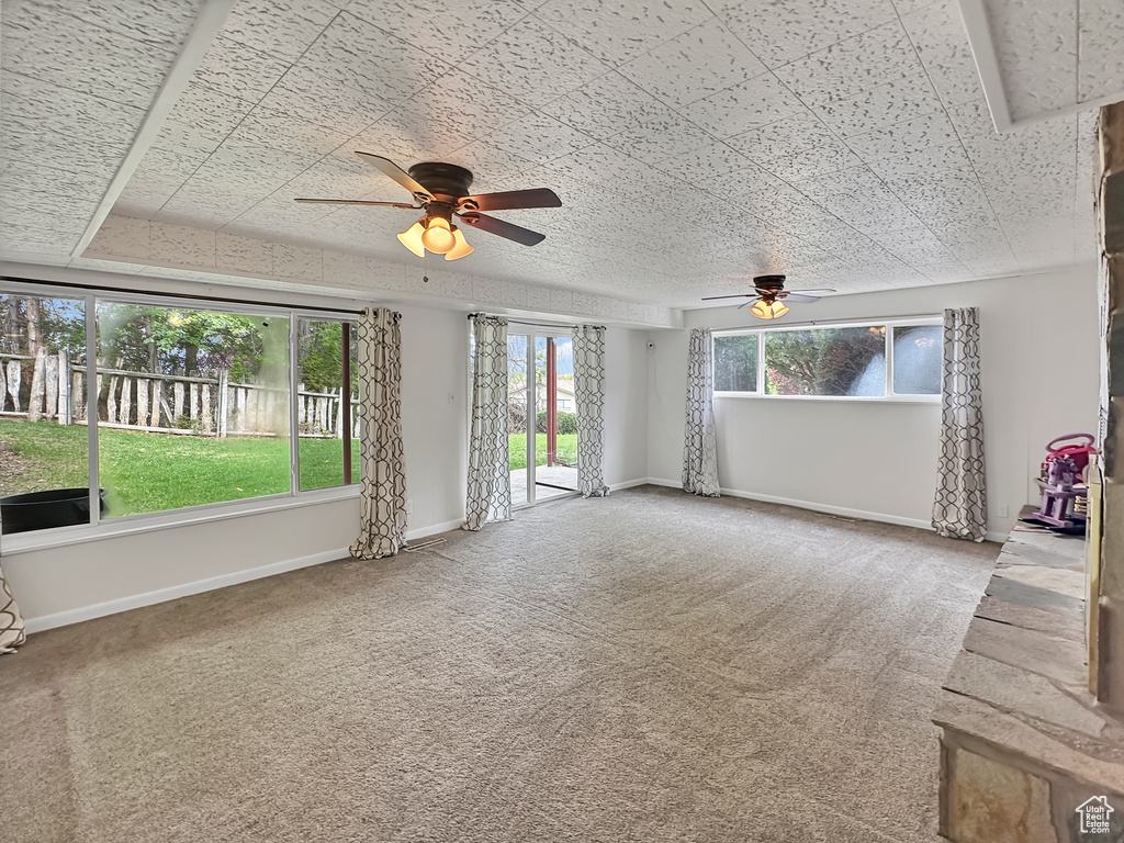 Carpeted spare room featuring ceiling fan and baseboards