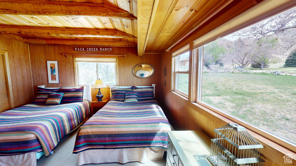 Bedroom with wooden ceiling, wood walls, and beam ceiling