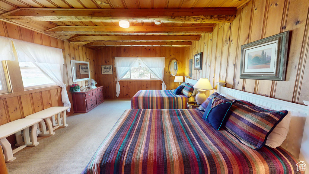 Bedroom featuring wooden walls, beamed ceiling, light colored carpet, and wooden ceiling
