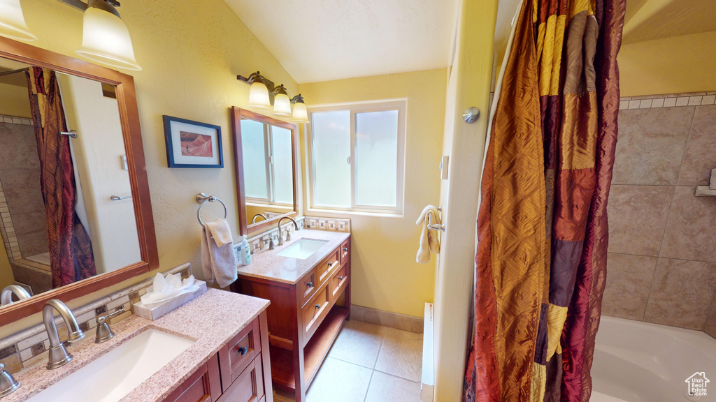 Full bath with shower / bath combo, lofted ceiling, a sink, and tile patterned flooring