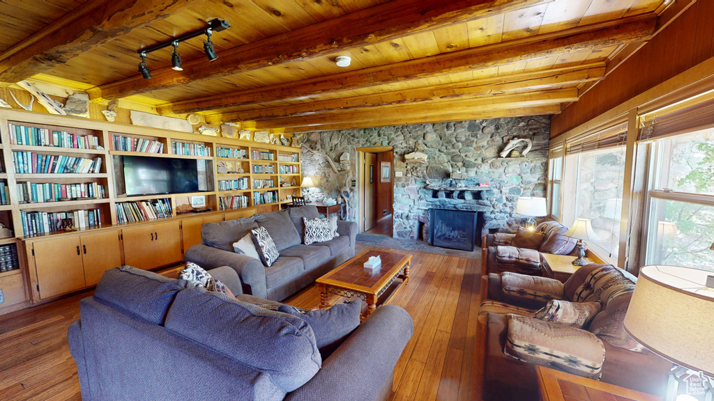 Living area featuring a fireplace, hardwood / wood-style floors, wooden ceiling, and beamed ceiling