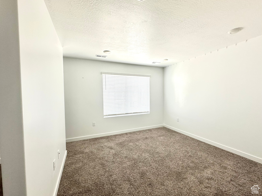 Carpeted spare room featuring a textured ceiling