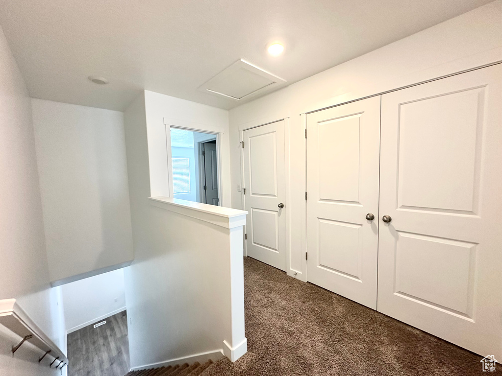 Hall with an upstairs landing, attic access, and dark carpet