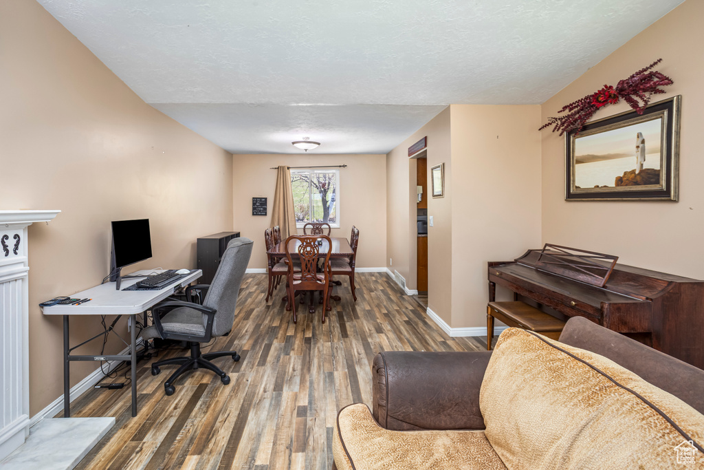 Office area with baseboards, wood finished floors, and a textured ceiling