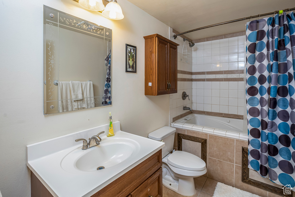 Bathroom with tile patterned floors, toilet, vanity, and tiled shower / bath
