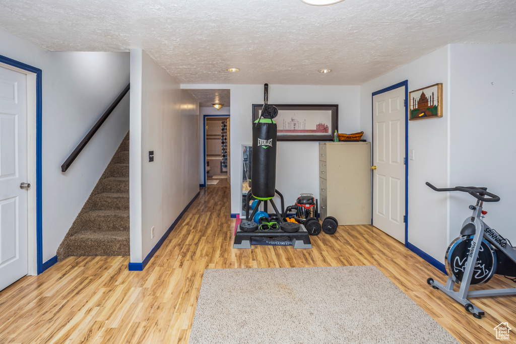 Workout area with baseboards, wood finished floors, and a textured ceiling