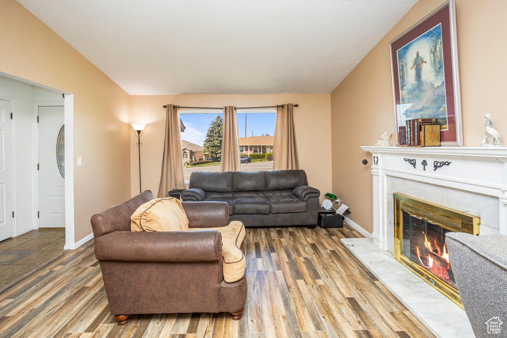 Living area with baseboards, wood finished floors, lofted ceiling, and a fireplace
