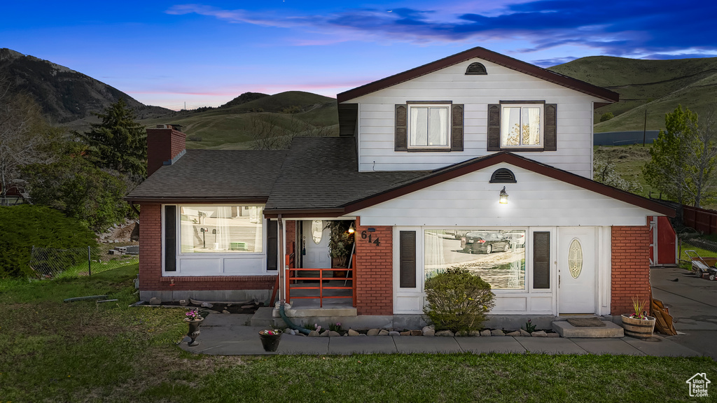 View of front of house with roof with shingles, a mountain view, and brick siding