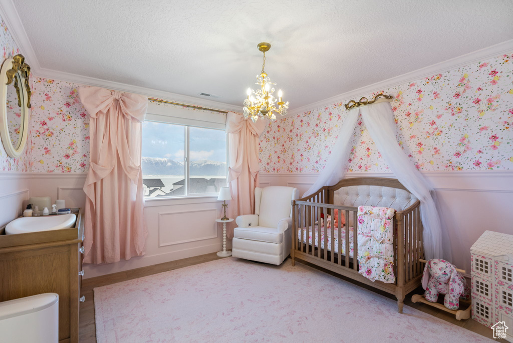 Bedroom with a wainscoted wall, crown molding, a notable chandelier, and wallpapered walls