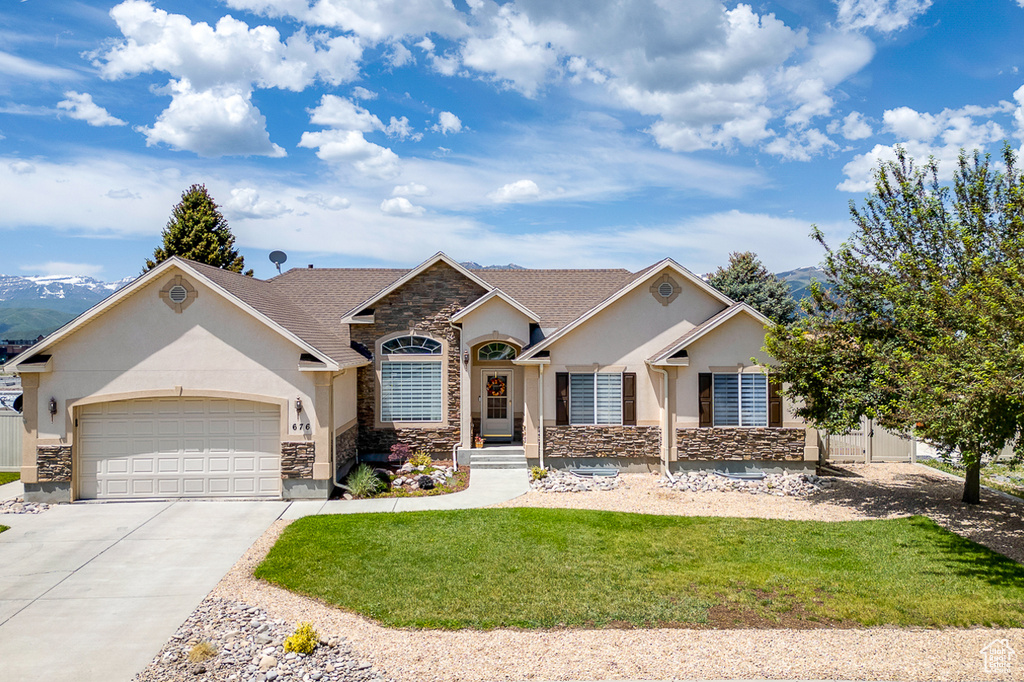 View of front of property with stucco siding, stone siding, an attached garage, and concrete driveway