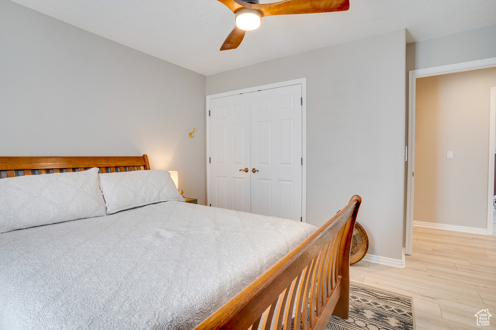 Bedroom featuring light wood finished floors, a closet, baseboards, and ceiling fan