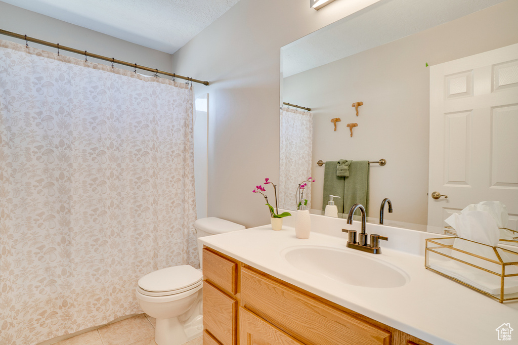 Bathroom with toilet, tile patterned floors, vanity, and a shower with curtain
