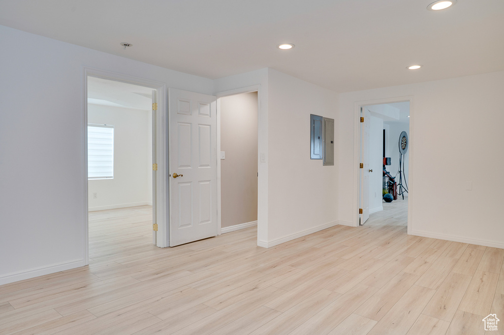 Empty room featuring light wood-type flooring, recessed lighting, baseboards, and electric panel
