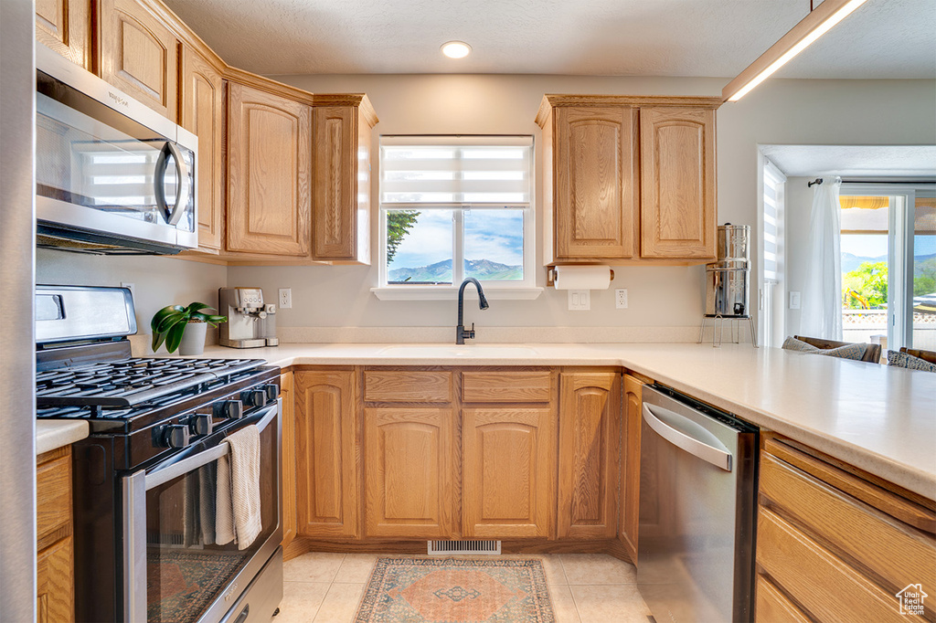 Kitchen with appliances with stainless steel finishes, a sink, light countertops, and recessed lighting