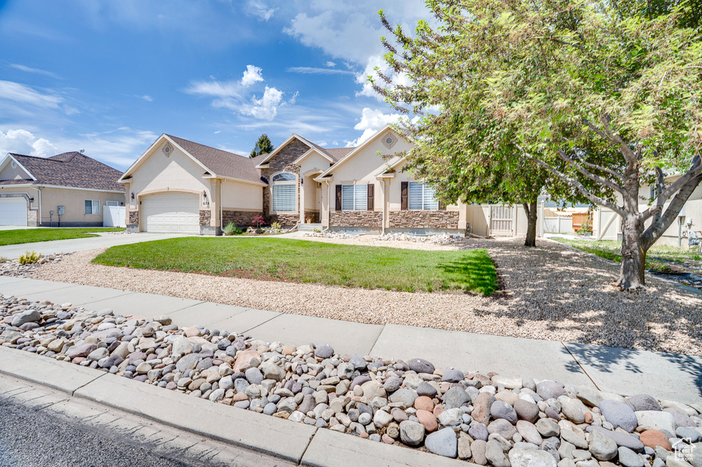 View of front facade with an attached garage, driveway, stucco siding, and stone siding