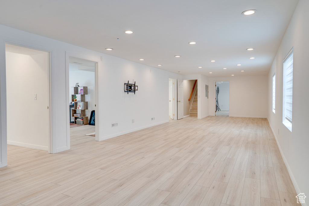 Unfurnished living room with stairs, light wood-style floors, recessed lighting, and baseboards