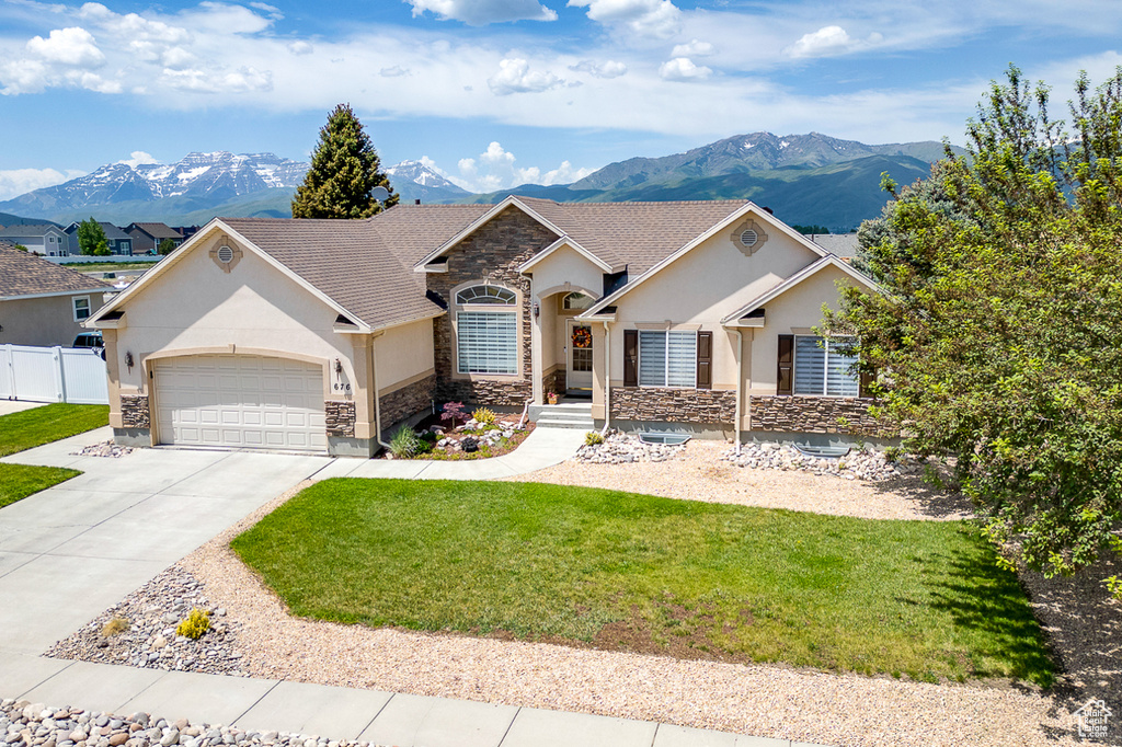 Single story home with stone siding, stucco siding, a mountain view, and an attached garage