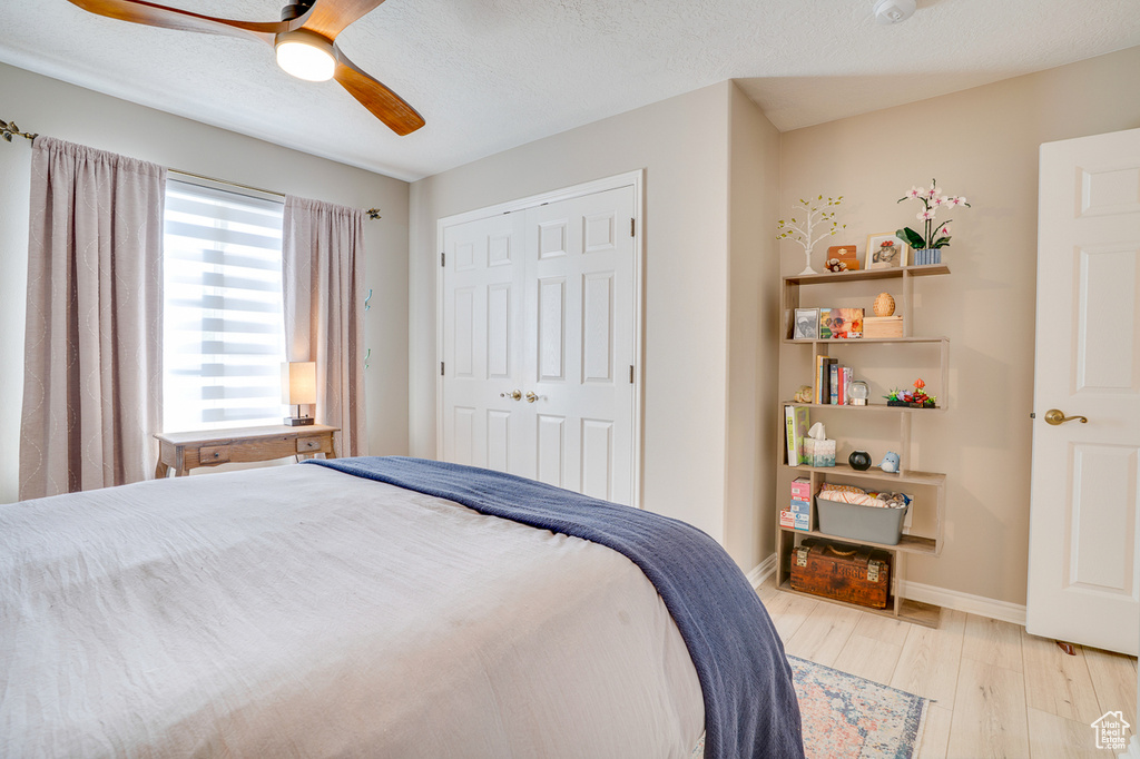 Bedroom featuring light wood-style floors, a ceiling fan, baseboards, and a closet