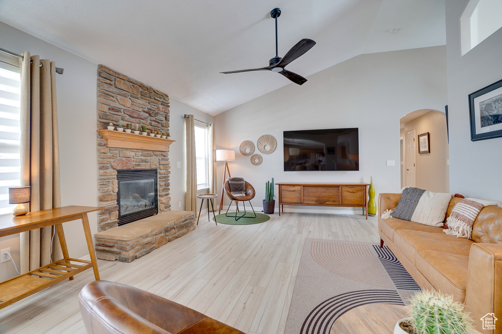 Living room featuring lofted ceiling, ceiling fan, arched walkways, wood finished floors, and a fireplace