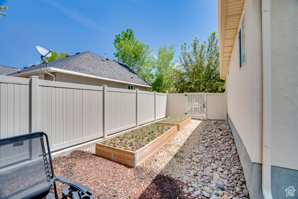 Fenced backyard featuring a vegetable garden and a gate