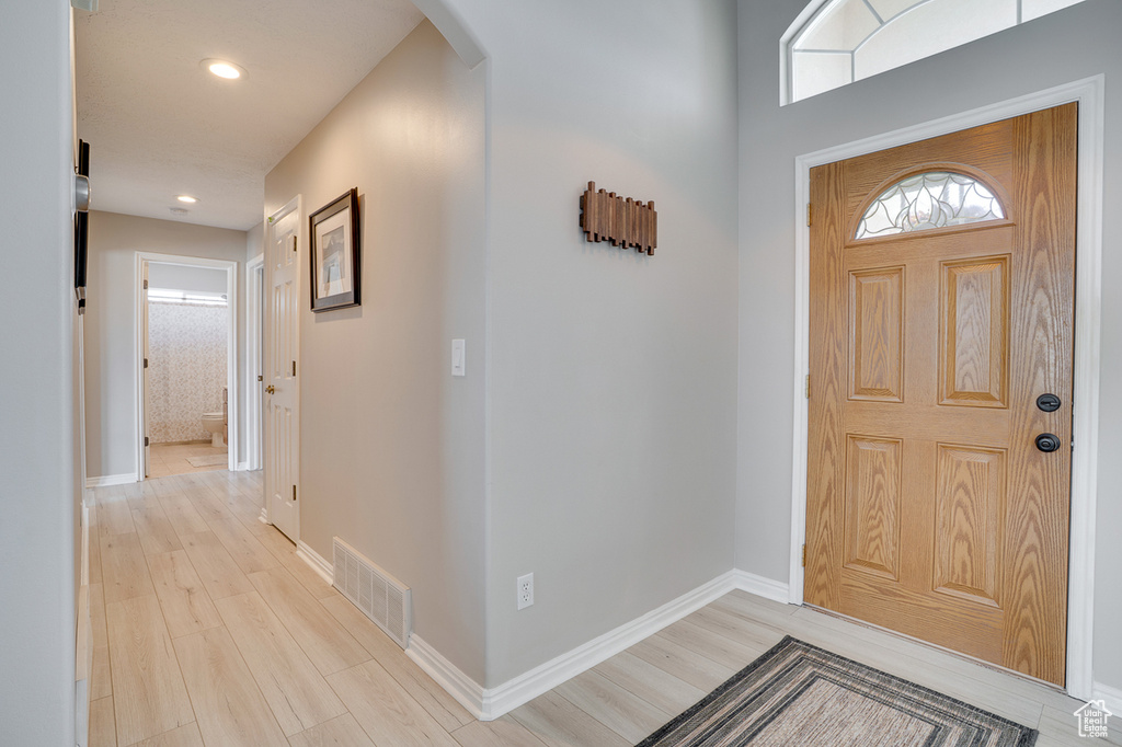 Entryway with arched walkways, light wood-style flooring, baseboards, and recessed lighting