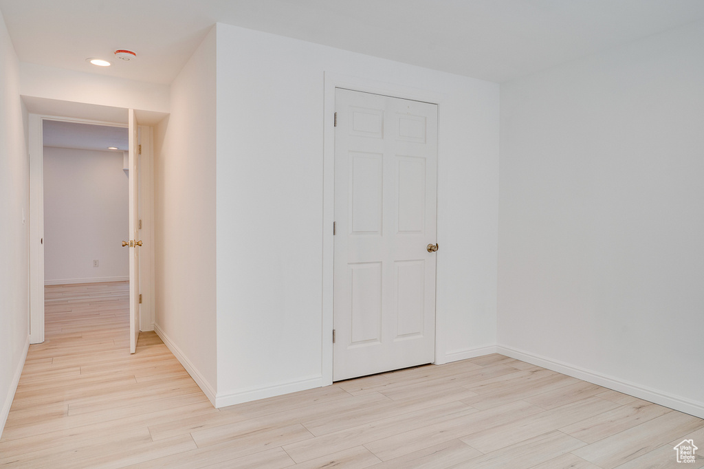 Empty room featuring light wood-style flooring, a smoke detector, baseboards, and recessed lighting