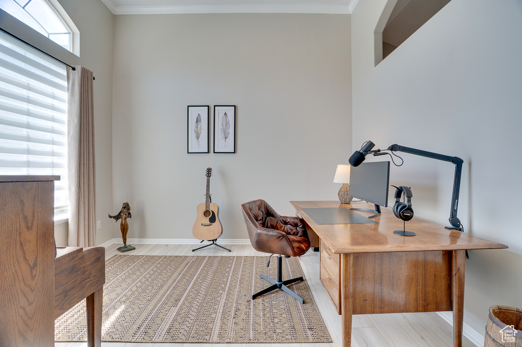 Office with ornamental molding, baseboards, and light wood-style flooring