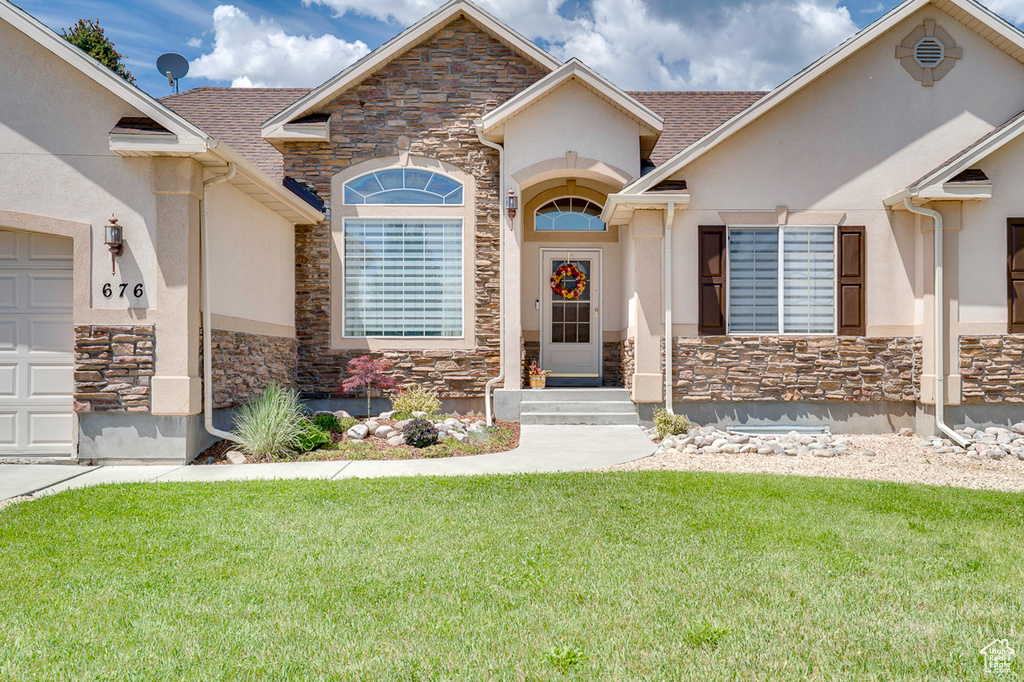 View of front of house featuring stone siding, stucco siding, a front lawn, and roof with shingles