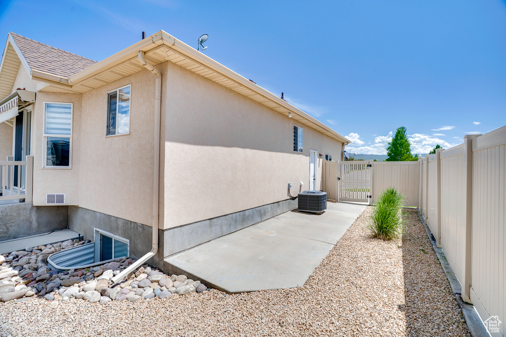 View of property exterior with a gate, stucco siding, and central air condition unit