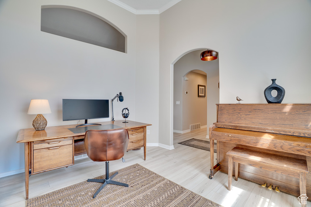 Office featuring ornamental molding, light wood-type flooring, baseboards, and arched walkways