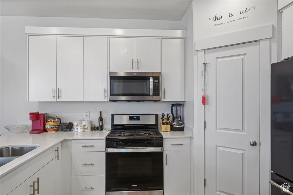 Kitchen featuring light countertops, appliances with stainless steel finishes, and white cabinetry