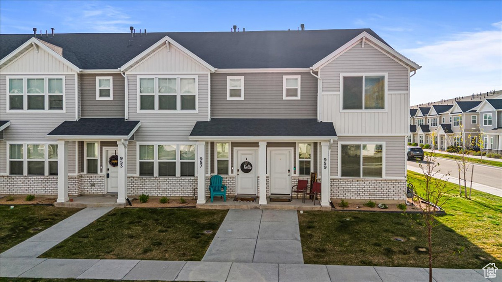 Multi unit property featuring covered porch, board and batten siding, a front yard, and stone siding