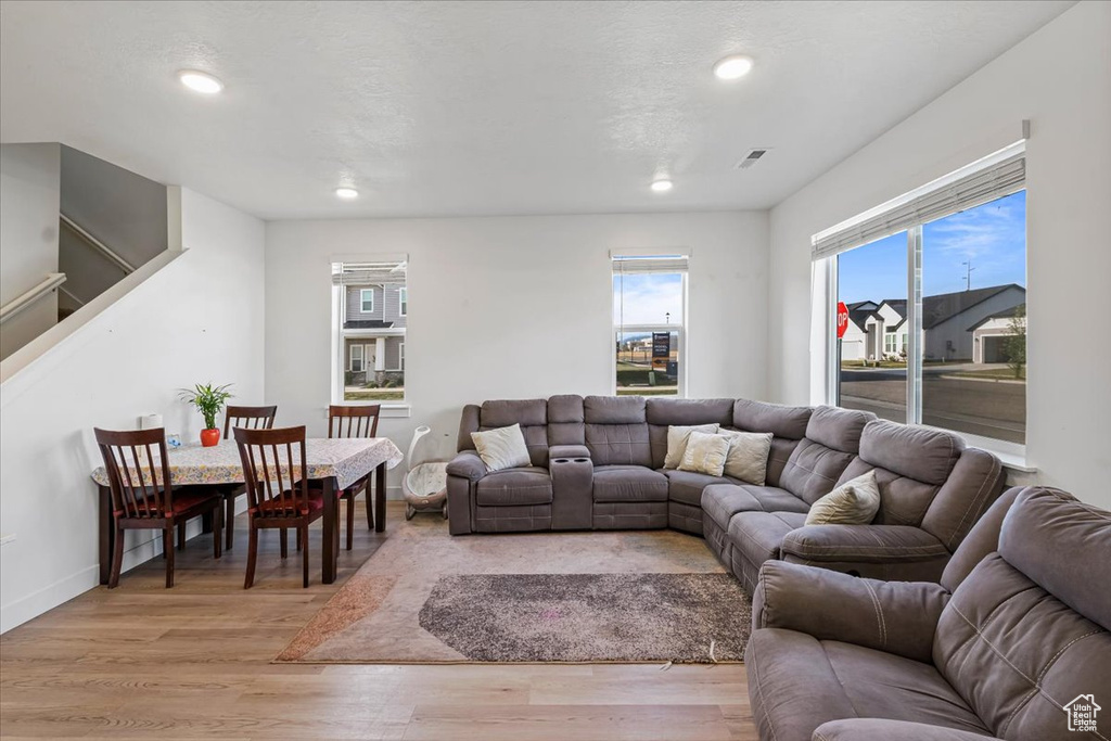 Living room with recessed lighting, light wood finished floors, baseboards, and stairs