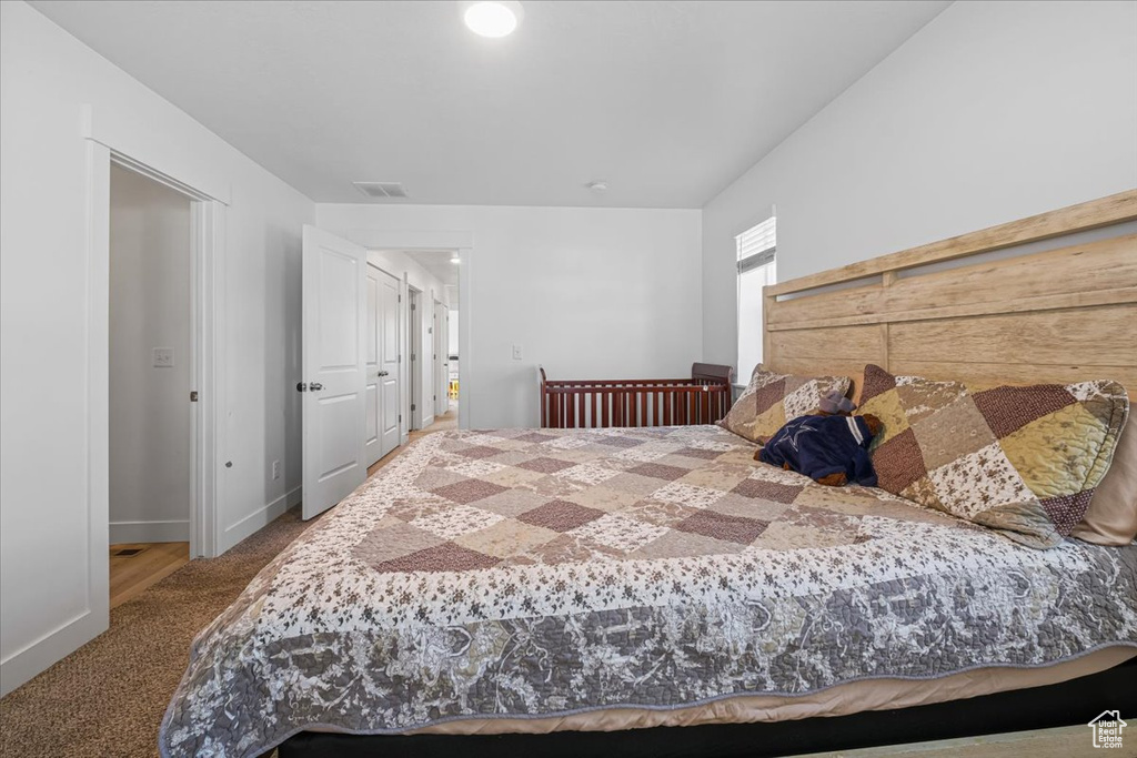 Carpeted bedroom featuring baseboards and visible vents