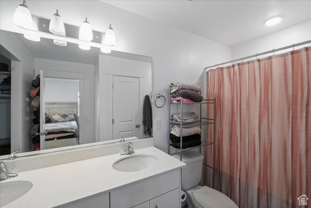 Full bathroom featuring toilet, double vanity, a sink, and connected bathroom
