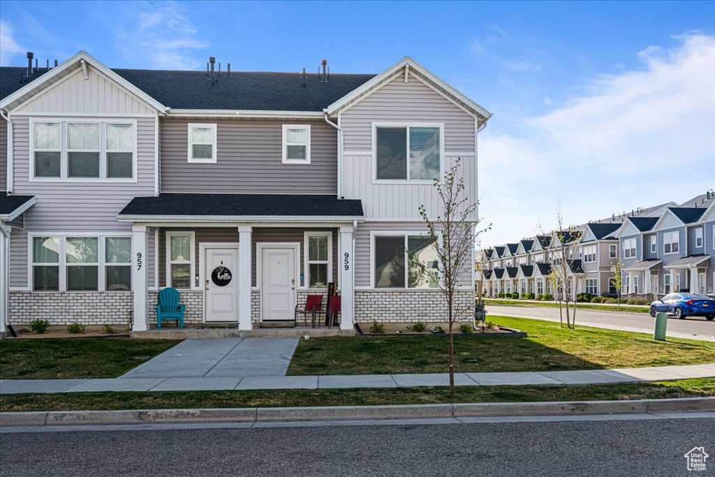 Multi unit property with board and batten siding, a residential view, a front yard, and roof with shingles