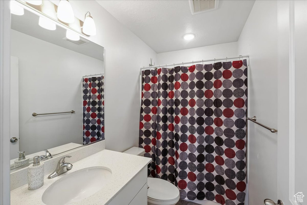 Full bath with visible vents, toilet, a shower with shower curtain, and vanity