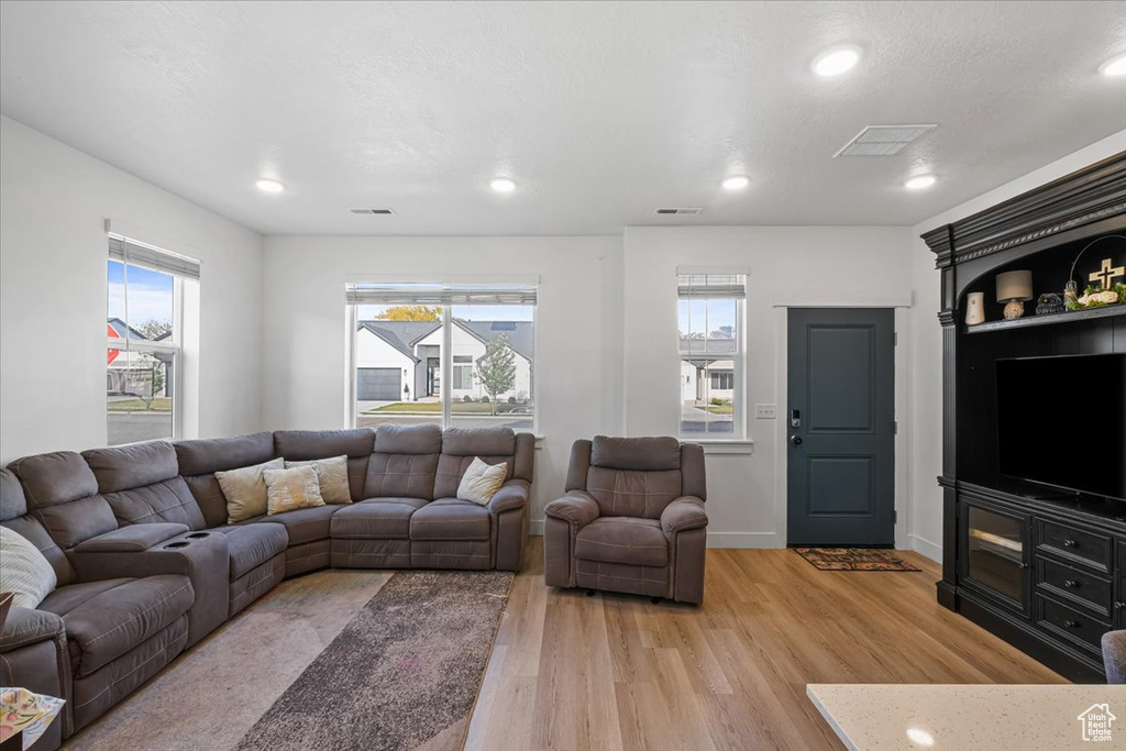 Living area with visible vents, light wood-style flooring, and recessed lighting