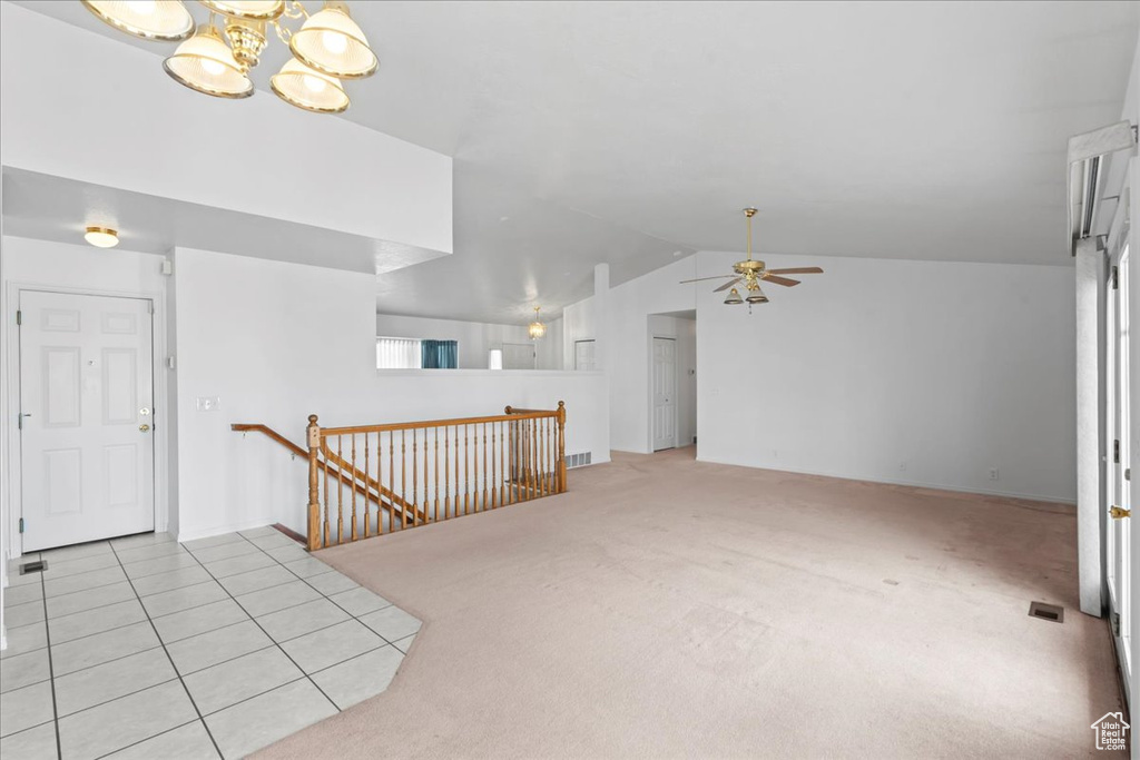 Entryway with visible vents, light carpet, vaulted ceiling, and ceiling fan with notable chandelier