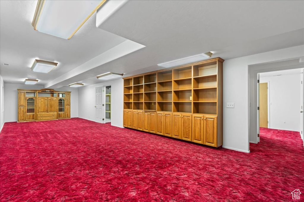 Finished basement with dark colored carpet and baseboards