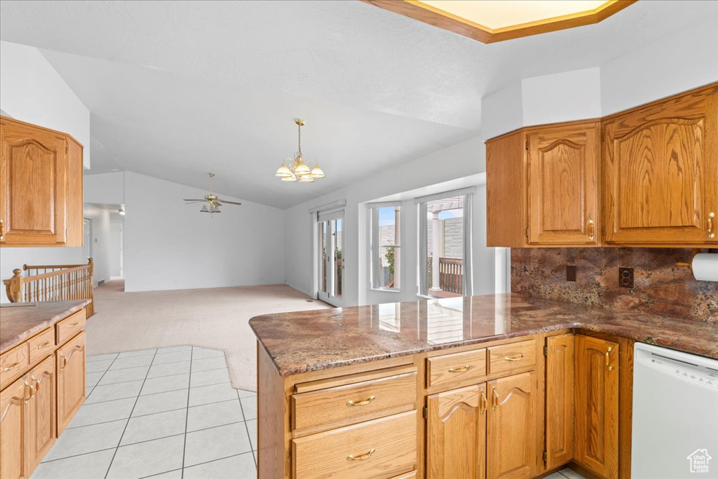 Kitchen with ceiling fan with notable chandelier, light carpet, dishwasher, a peninsula, and lofted ceiling