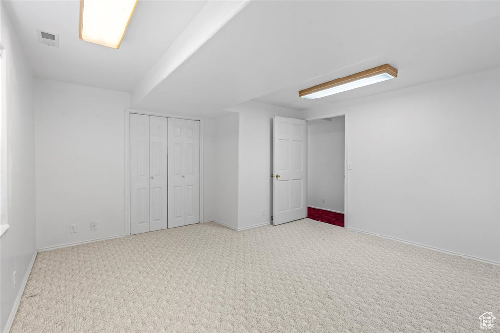 Basement featuring visible vents, baseboards, and light carpet