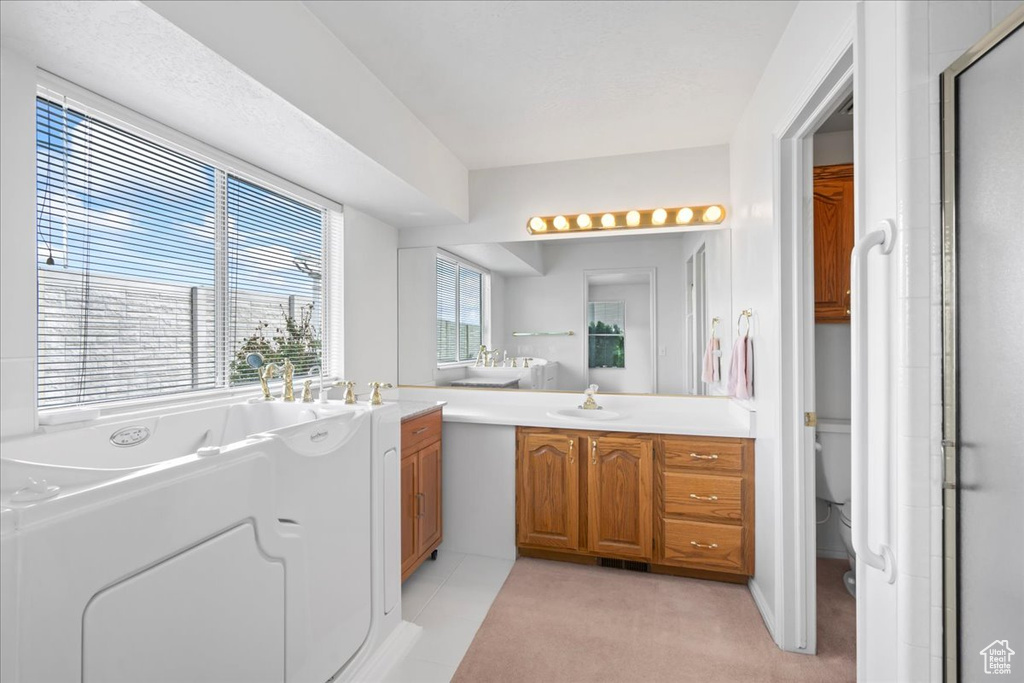 Bathroom with toilet, vanity, a washtub, and a shower with door
