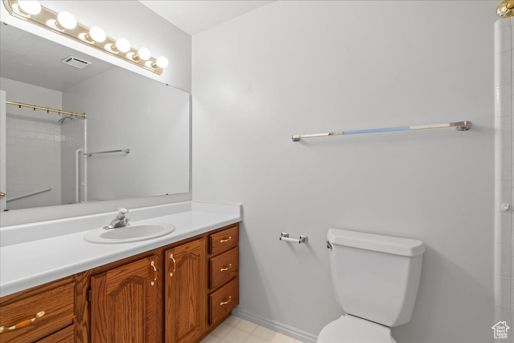 Bathroom featuring visible vents, baseboards, walk in shower, toilet, and vanity